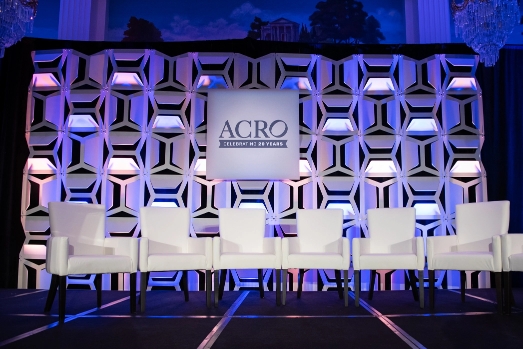 Stage at ACRO event with empty chairs for presenters